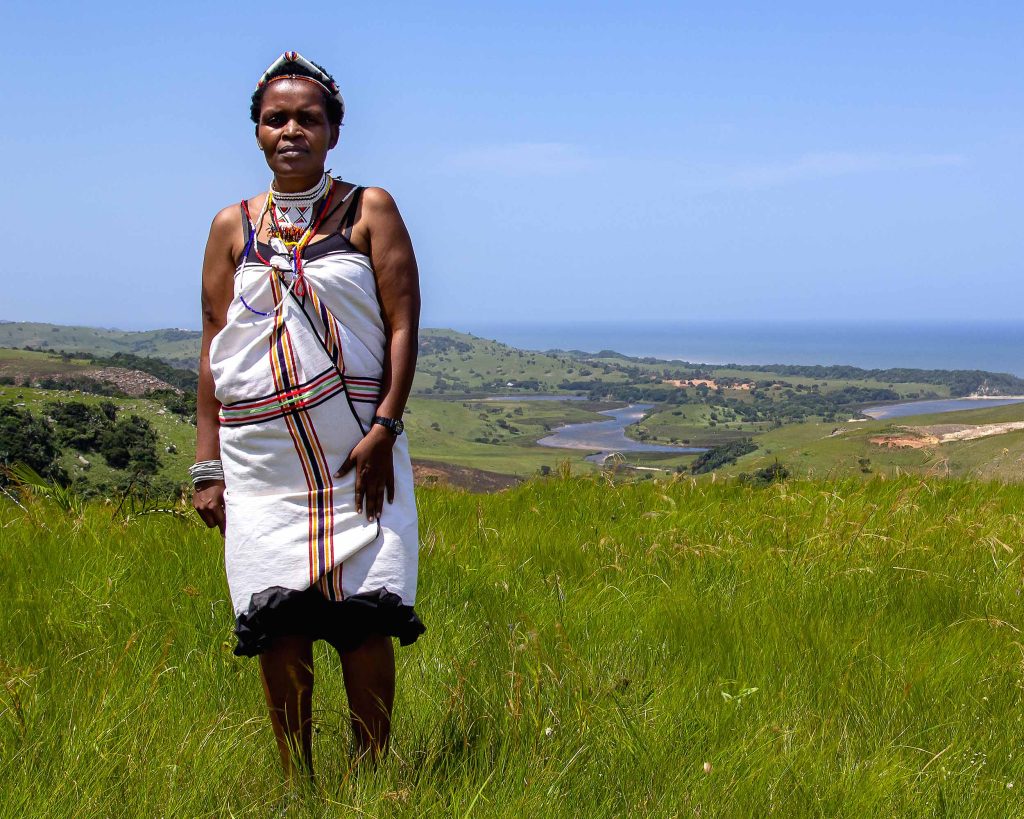 Nonhle stands on the coast wearing traditional attire of the Mpondo people.