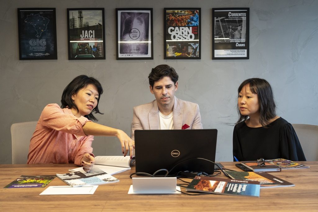 Marcel Gomes working at a laptop with two colleagues.